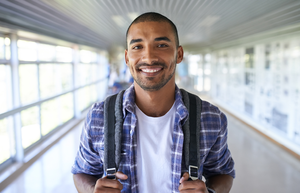 Student Smiling in Hallway Holding Backpack Straps
