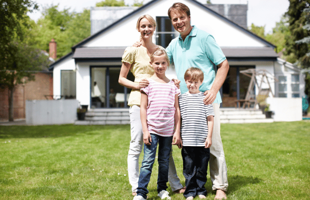 Family standing in backyard with their home in the background