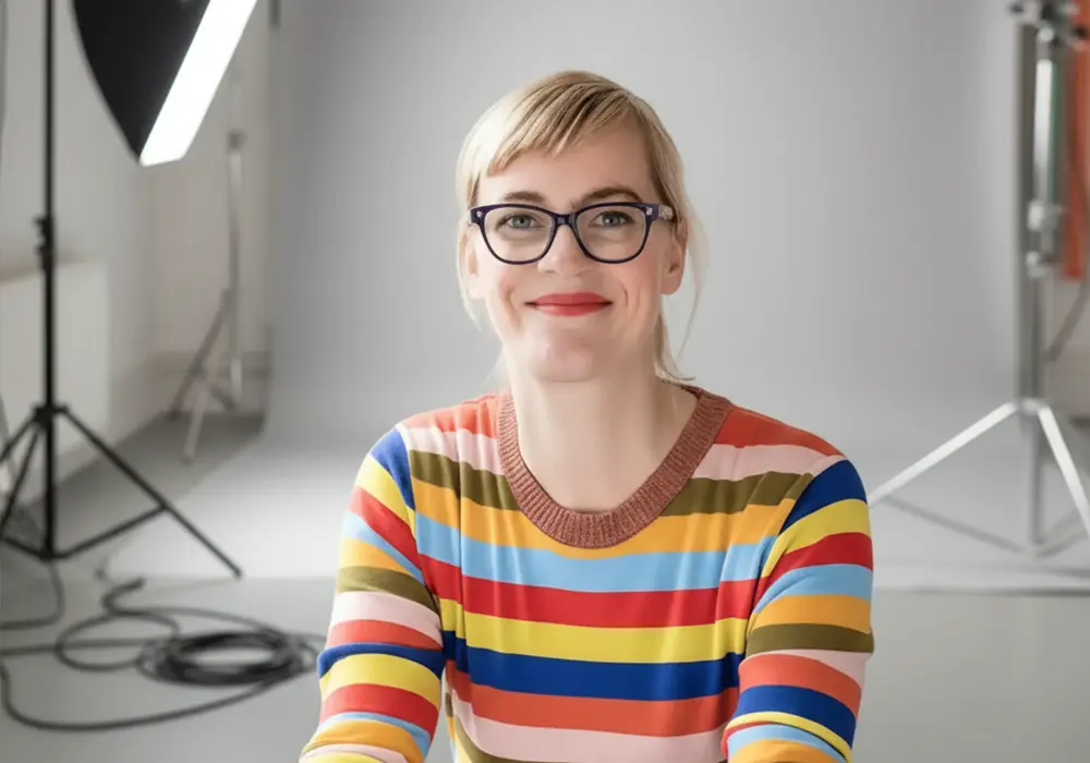 Older man sits on a sofa talking on the phone and using a laptop