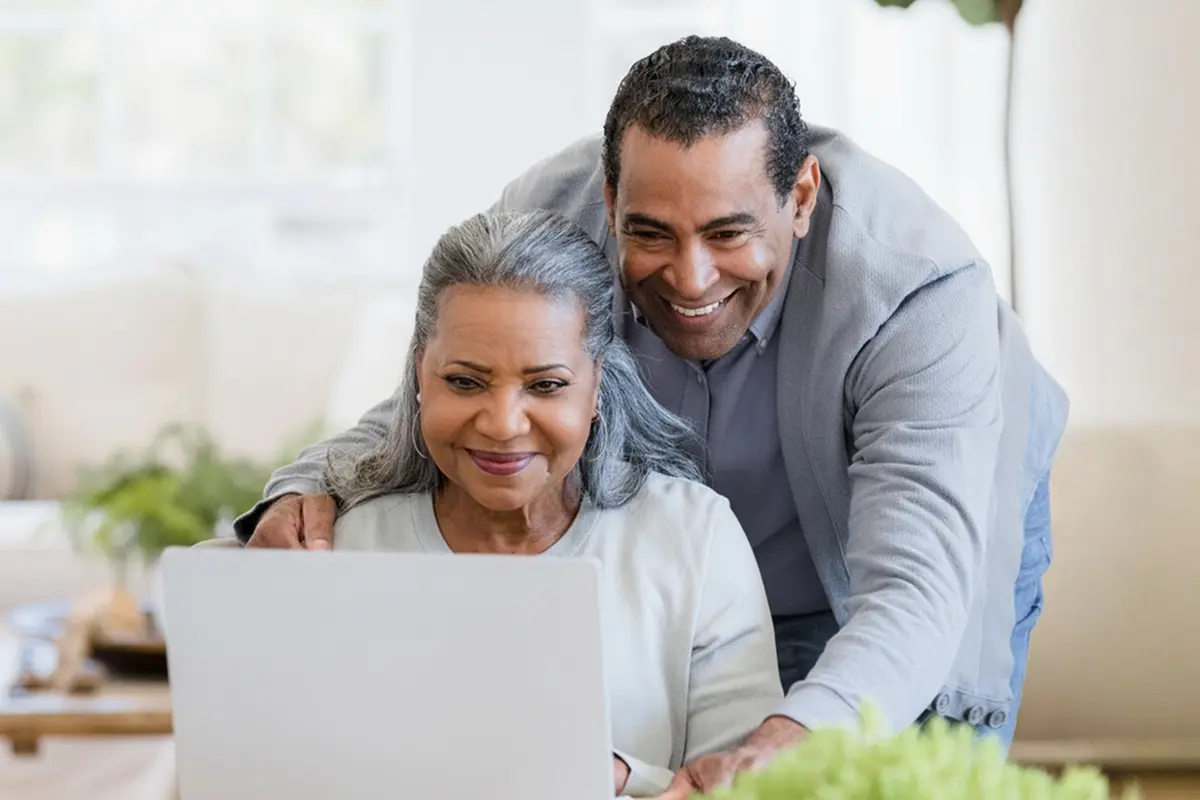 Smiling couple using a laptop together at home for online banking.