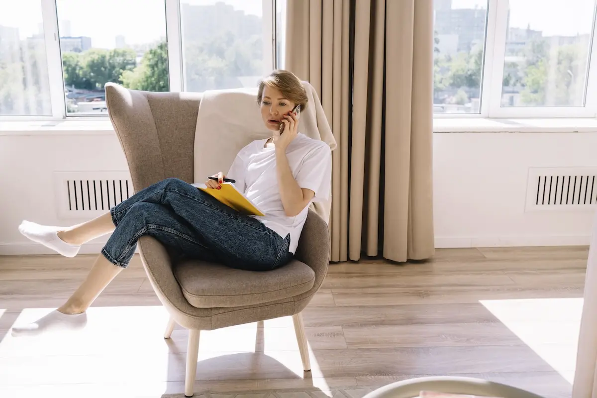 Creative professional relaxing at home while managing finances on her phone, illustrating the importance of an emergency fund for irregular creative income.