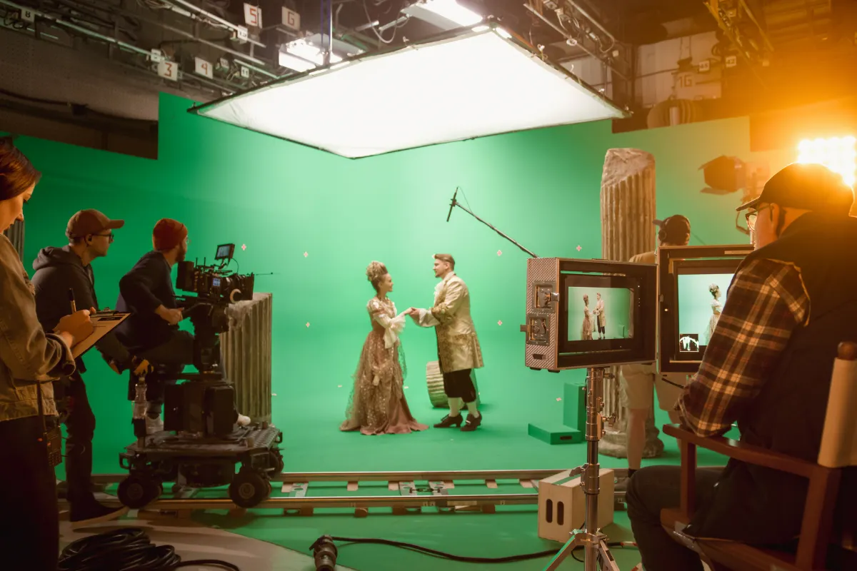 Film crew capturing a period‑costume scene on a green‑screen soundstage, highlighting the kind of creative industry professionals Creative Arts Financial empowers with specialized banking for artists and gig workers