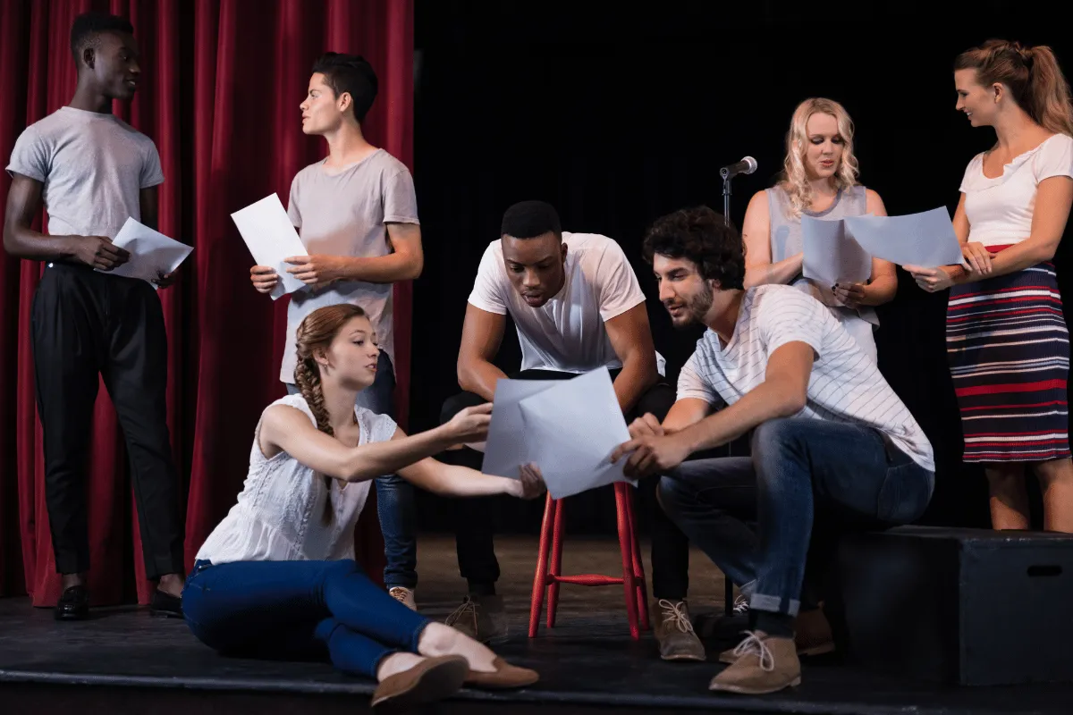 Actors rehearsing with scripts on stage, highlighting the need for flexible banking solutions for performers.