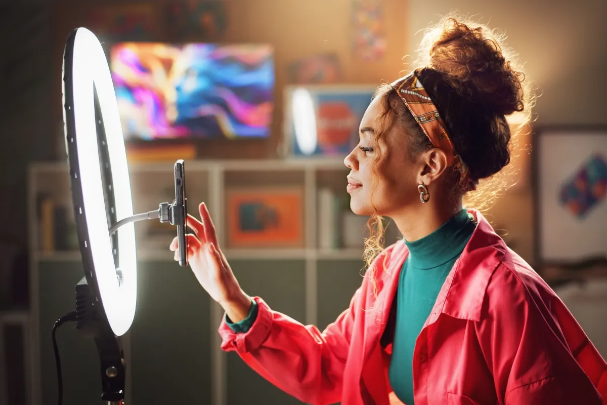 Content creator recording with a smartphone and ring light in a colourful creative workspace.